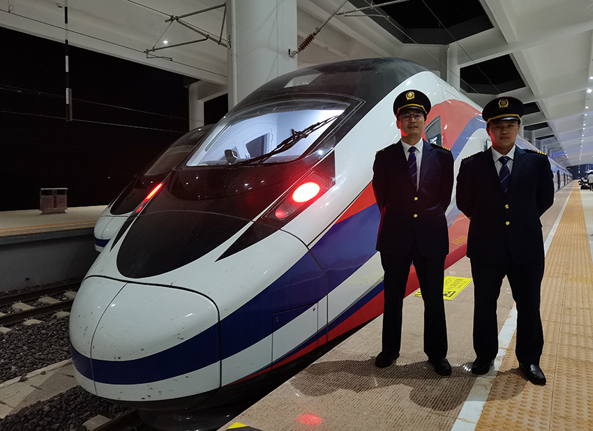 劉銀能（右一）與中國師父鄔俊鴻在動車組前合影。受訪者供圖